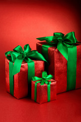 Red gift boxes with green ribbons and bow on red holiday background . Merry christmas card. Winter xmas theme.Boxing day
