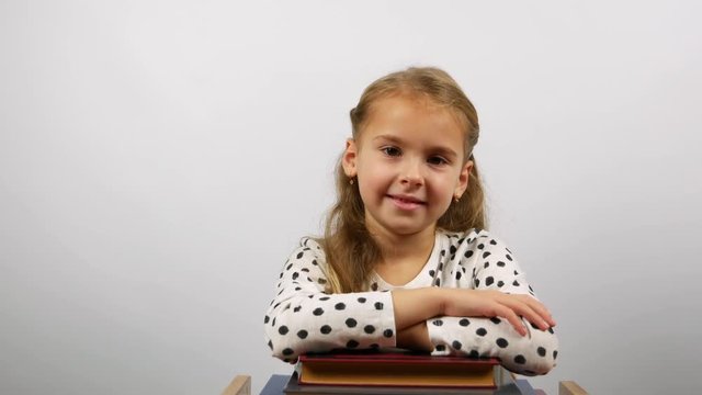 Smiling girl holding a pile of books looking into the camera. Concept of obtaining knowledge and skills