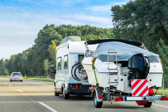 Caravan and trailer for motor boats on road in Switzerland