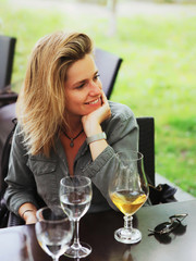 Young woman drinking with glass of beer at street restaurant