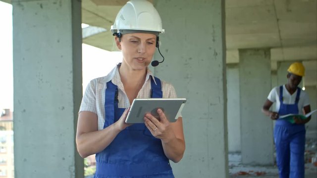 Female and fro-american men are constructors considered building plan on a tablet - Powered by Adobe