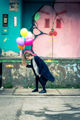 girl holding balloons at abandoned industrial area