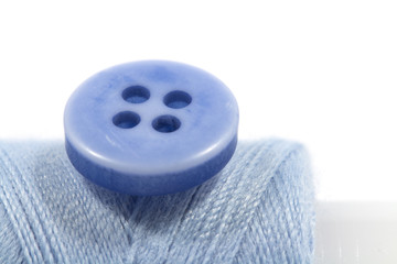 The needle, button and a sewing reel. Conceptual photography of tailor's work.