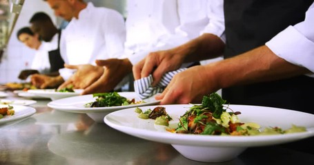 Team of chefs garnishing meal on counter 