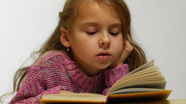 Close-up view of a girl reading a book. A young cute girl reads a book in a whisper.