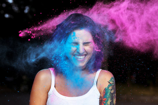 Cheerful young woman with dry powder Holi exploding around her
