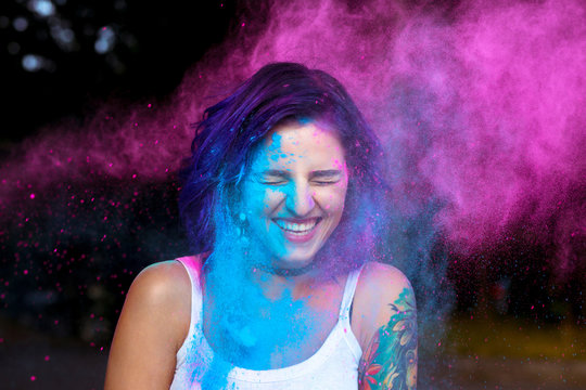 Laughing young woman with dry powder Holi exploding around her