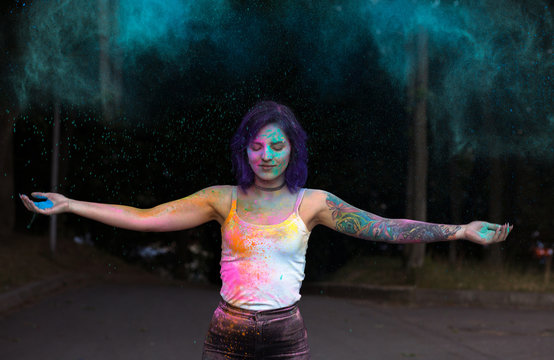 Magnificent woman with purple hair tossing up colorful Holi powder