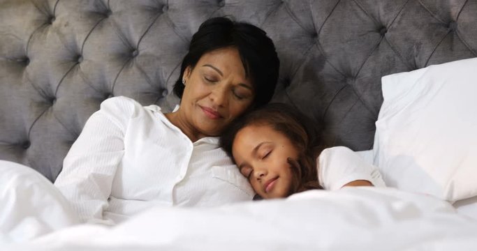 Grandmother and granddaughter sleeping together in bedroom 