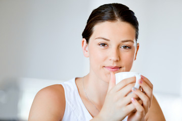 Happy young woman with cup of tea or coffee at home