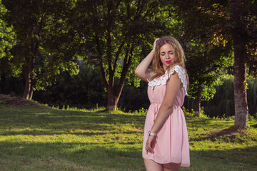 Young woman in pink dress posing in the park