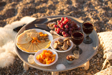 Outdoors picnic with wine, cheese, grapes and dried fruits