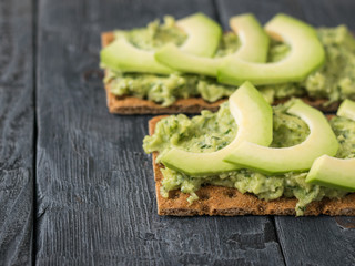 Fresh crisp bread with cream and avocado on a rustic table.