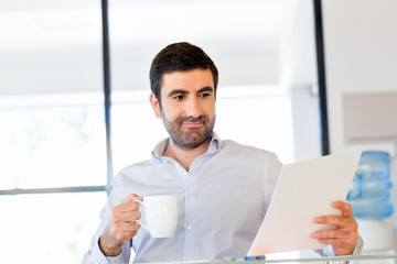 Handsome young man holding paper in office