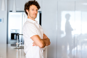 Portrait of a smart young man standing in kitchen