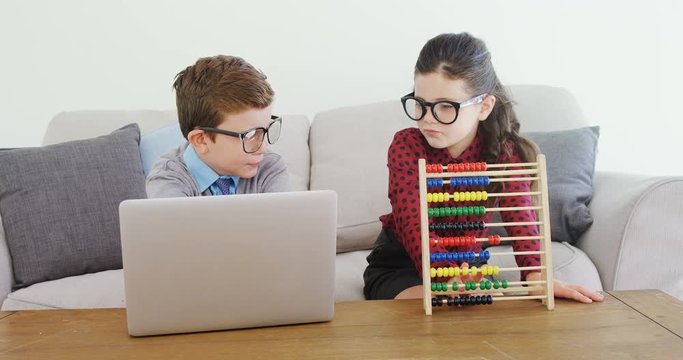 Kids as business executive disusing over laptop 