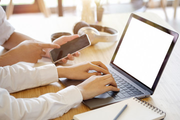 Two business people with laptop and smartphone meeting in modern office.