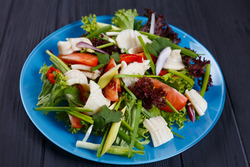 Delicious fresh salad with squid on black kitchen background, close up. Pan-Asian, oriental cuisine, tasty appetizing seafood