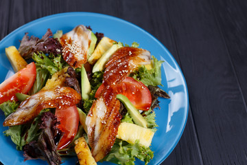 Close up of fresh delicious salad with smoked eel and pineapple slices.  Pan-Asian, oriental cuisine, tasty appetizing seafood