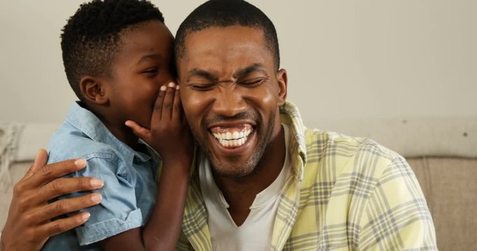 African American son whispering in his fathers ear 