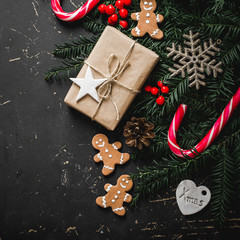 Christmas background with gingerbread, xmas tree and decoration on dark wooden board.