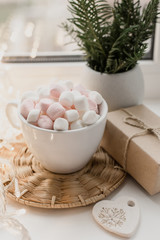 Cup of hot chocolate and marshmallow in the background of Christmas decorations.