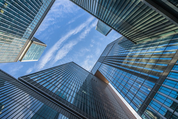 Bottom view of modern skyscrapers in business district against blue sky.
