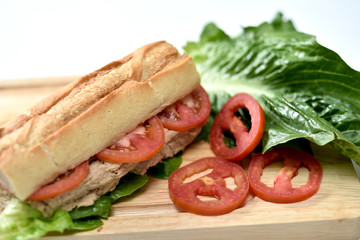 closeup photo of sandwich with tuna and vegetables on rye bread on wood background