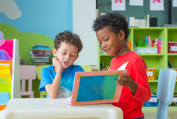 Two boy kid sit on table and reading tale book  in preschool library,Kindergarten school education...