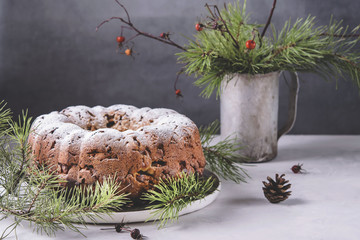 Traditional homemade christmas cake with nuts and dried fruit on light grey background. Christmas decoration. Selective focus. Vintage tone style 