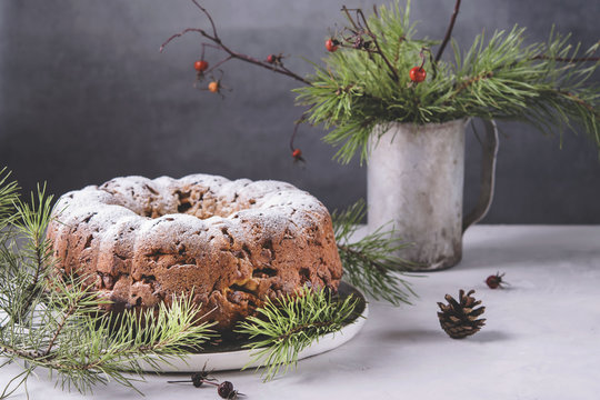 Traditional homemade christmas cake with nuts and dried fruit on light grey background. Christmas decoration. Selective focus. Vintage tone style 