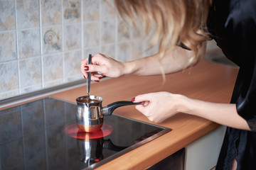 Cooking coffee in traditional copper turkey on a stove - kitchen interior