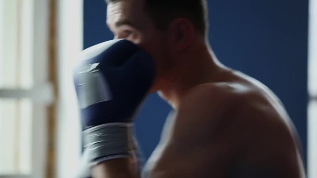 Holds a professional boxer shadow Boxing wearing Boxing gloves with his shirt off. A vertical camera movement in close-up. Pan.