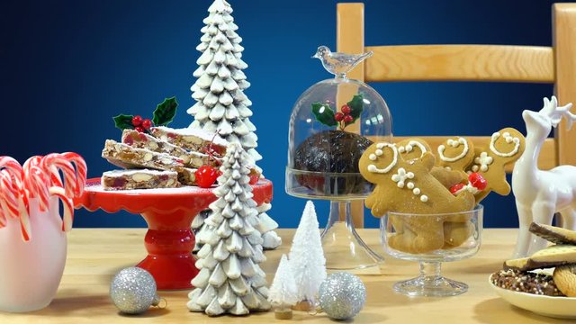 Festive table with traditional English and European style Christmas food including panforte cake, plum pudding, gingerbread cookies, and chocolate covered shortbread.
