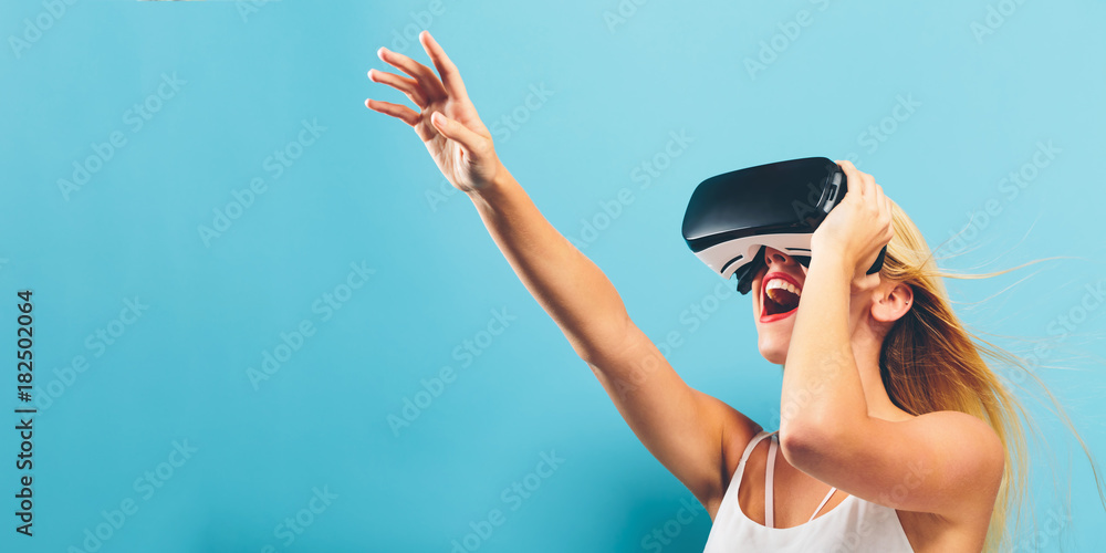 Wall mural Happy young woman using a virtual reality headset