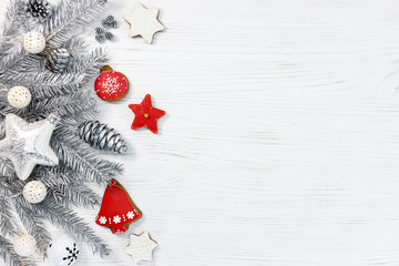 silver christmas tree branches with lights, star and gingerbread cookies on white wooden background flat view