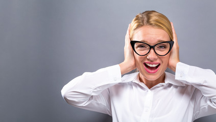 Young woman blocking her ears on a solid background