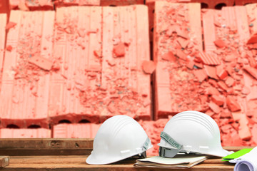 safety helmet plastic and blueprint on wood. concept construction with blur brick background