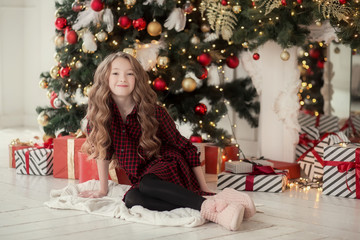 Smiling girl sitting under Christmas tree