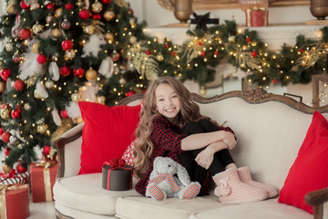 Smiling girl sitting under Christmas tree