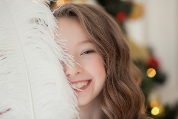 Smiling girl with feather near Christmas tree