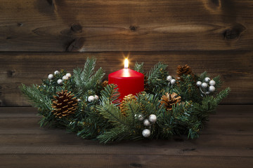 First Advent - Decorated Advent wreath with a red burning candle on a wooden background
