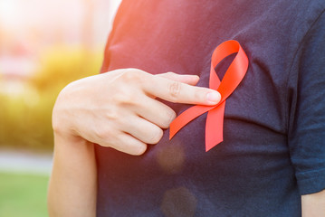 World Aids Awareness concept. Woman hands holding red AIDS awareness ribbon.