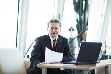 Fototapeta premium Confident businessman with documents on a laptop