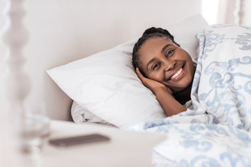 Smiling young African woman waking up in her bed