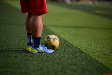 Unidentified group of male football players playing amateur football match on sunny summer day on simple sports venue