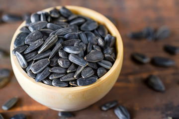 Unpeeled sunflower seeds in wooden bowl