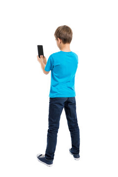 Back view of boy in t-shirt and jeans talking on mobile phone