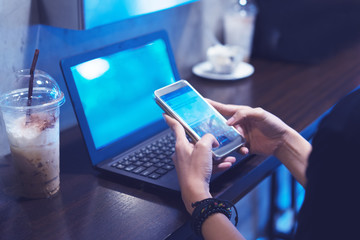 Women's hands holding smartphone with coffee on notebook place
