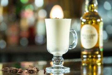 Glass of pina colada cocktail at colorful bar counter background.